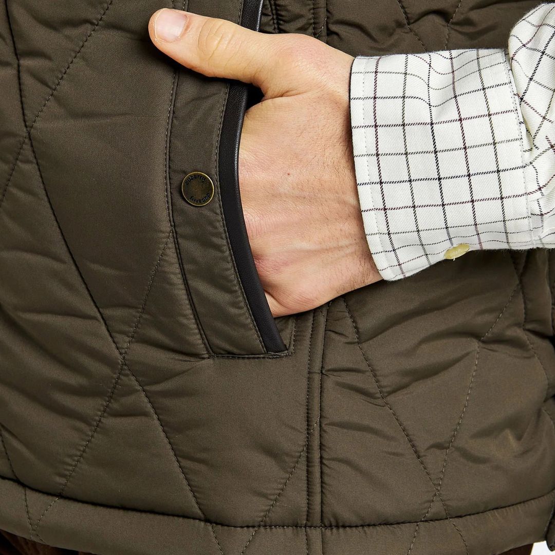 Close-up of a hand wearing a quilted brown jacket with a buttoned sleeve.