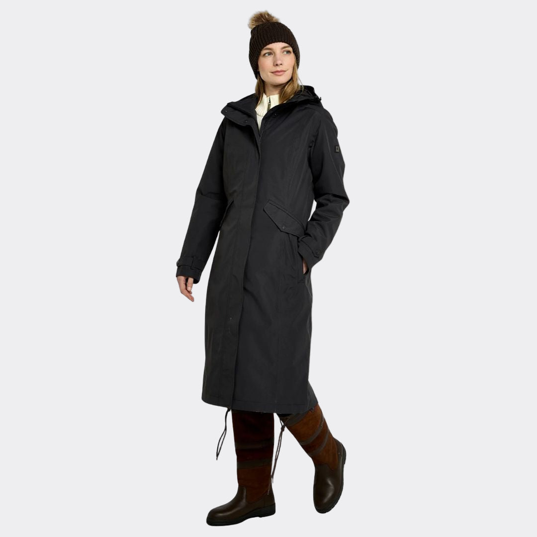 Person wearing a long black coat, brown boots, and a beanie on a white background