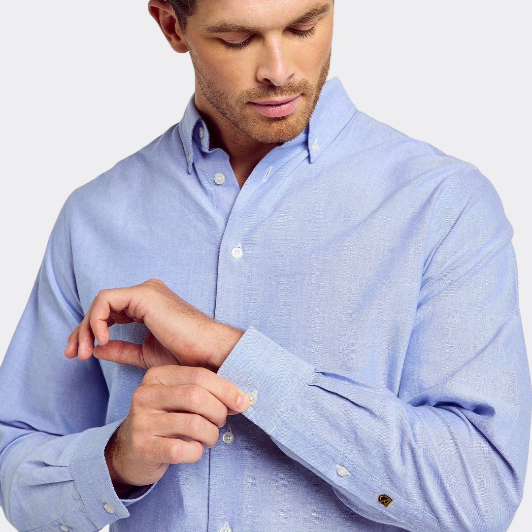 Man wearing a light blue dress shirt with rolled-up sleeves on a white background