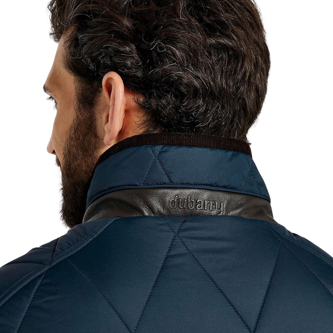 Person wearing a navy blue jacket with leather collar, featuring the brand 'Dubarry'.