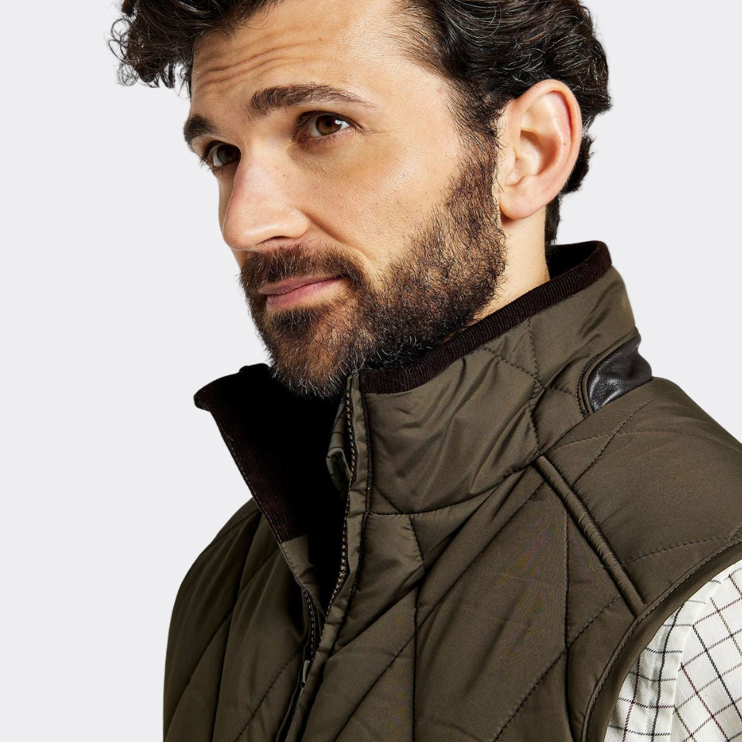 Man wearing a brown quilted vest on a white background