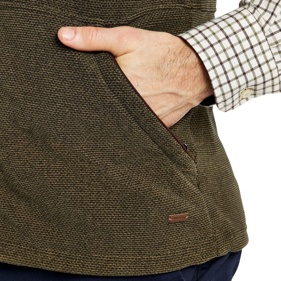 Close-up of a hand in a brown jacket pocket with a checkered sleeve.