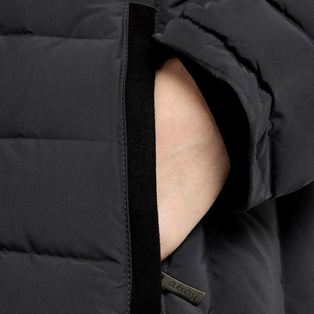Close-up of a black puffer jacket with a brand logo on a dark background