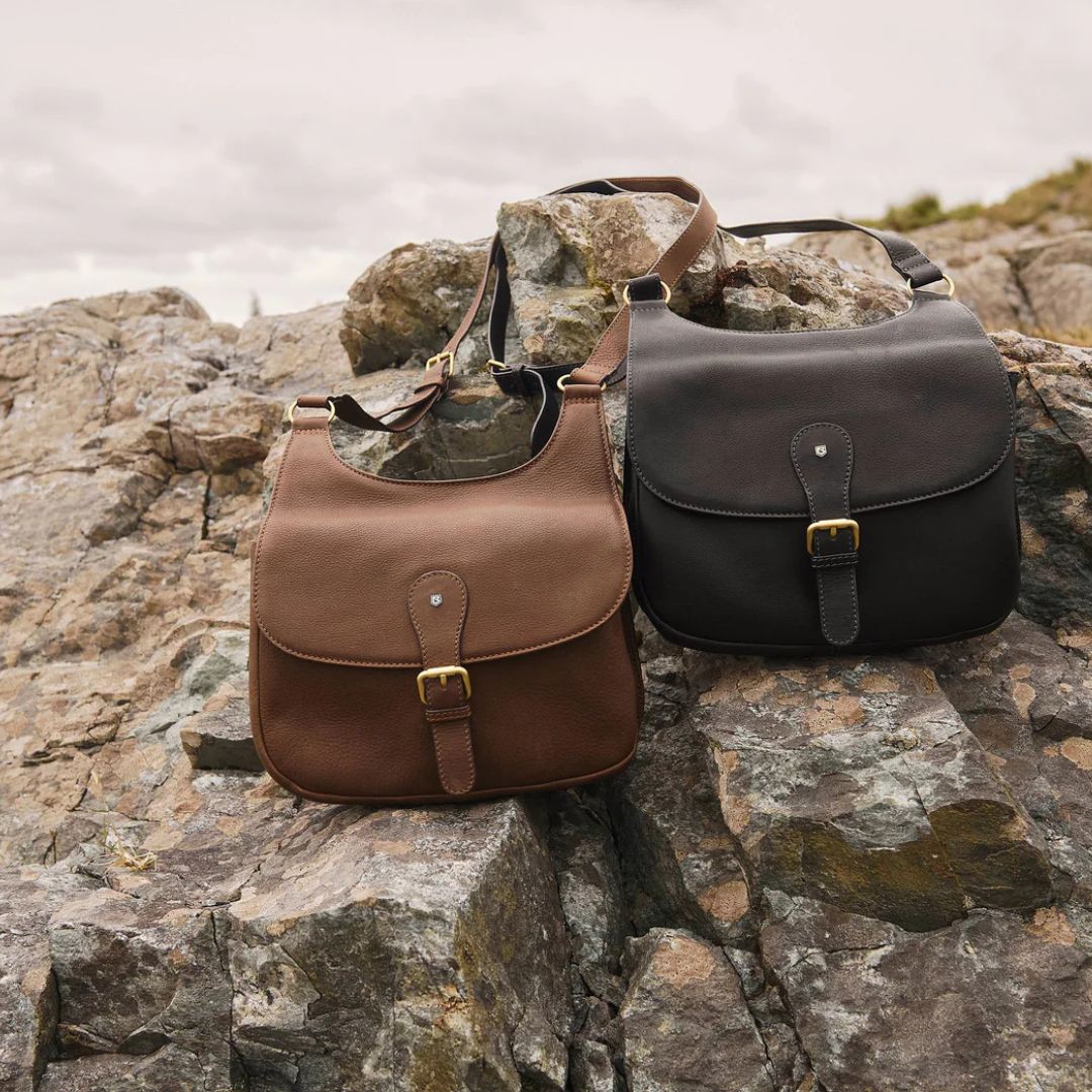 Two leather bags, one brown and one black, on a rocky surface.