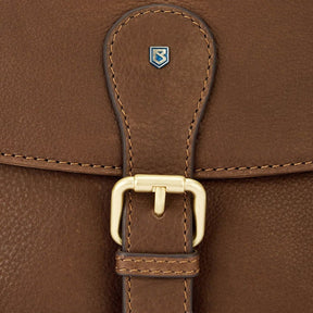 Close-up of a brown leather bag with a gold buckle and visible brand logo.