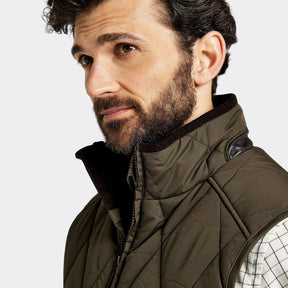 Man wearing a brown quilted vest on a white background