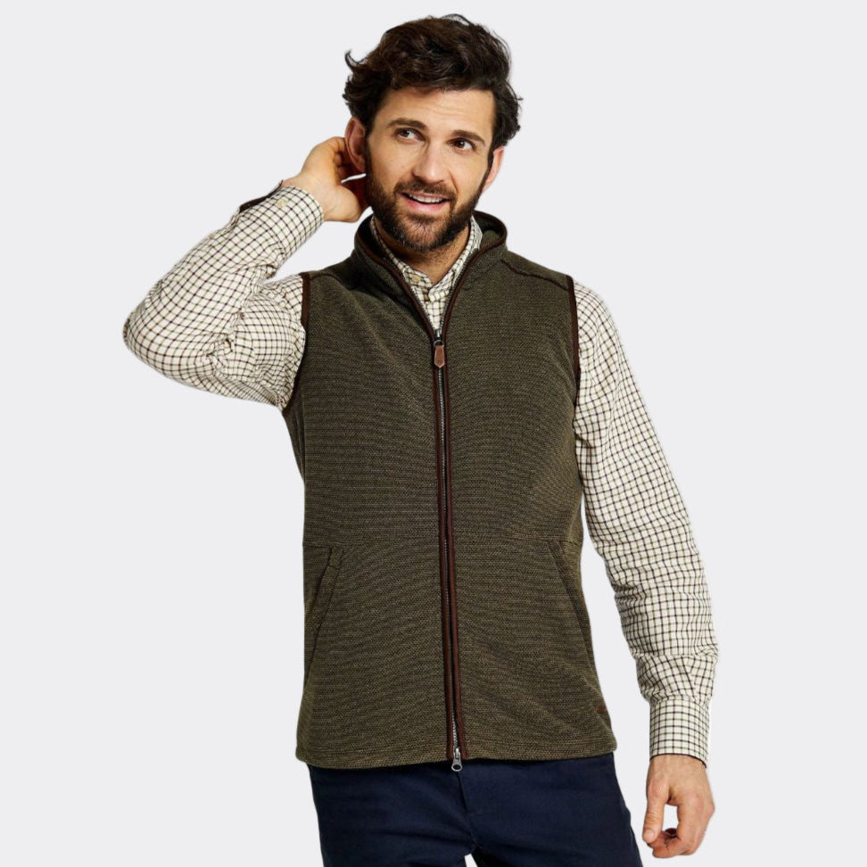 Man wearing a green vest over a checkered shirt on a white background