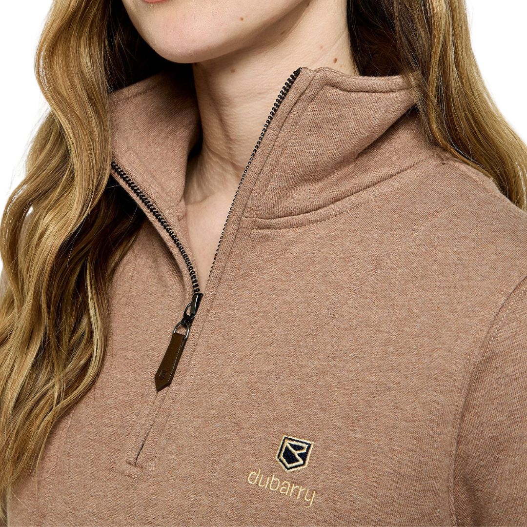 Close-up of a person wearing a brown Dubarry jacket with a logo.