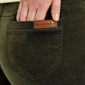 Close-up of a person's hand in the pocket of green Dubarry jeans.