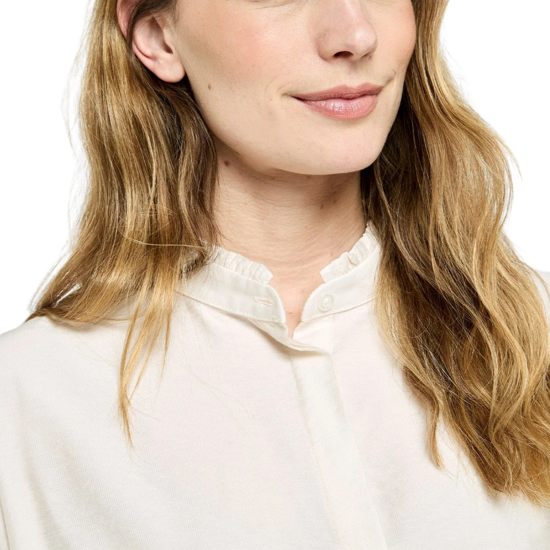 Close-up of a person wearing a white shirt with a plain background