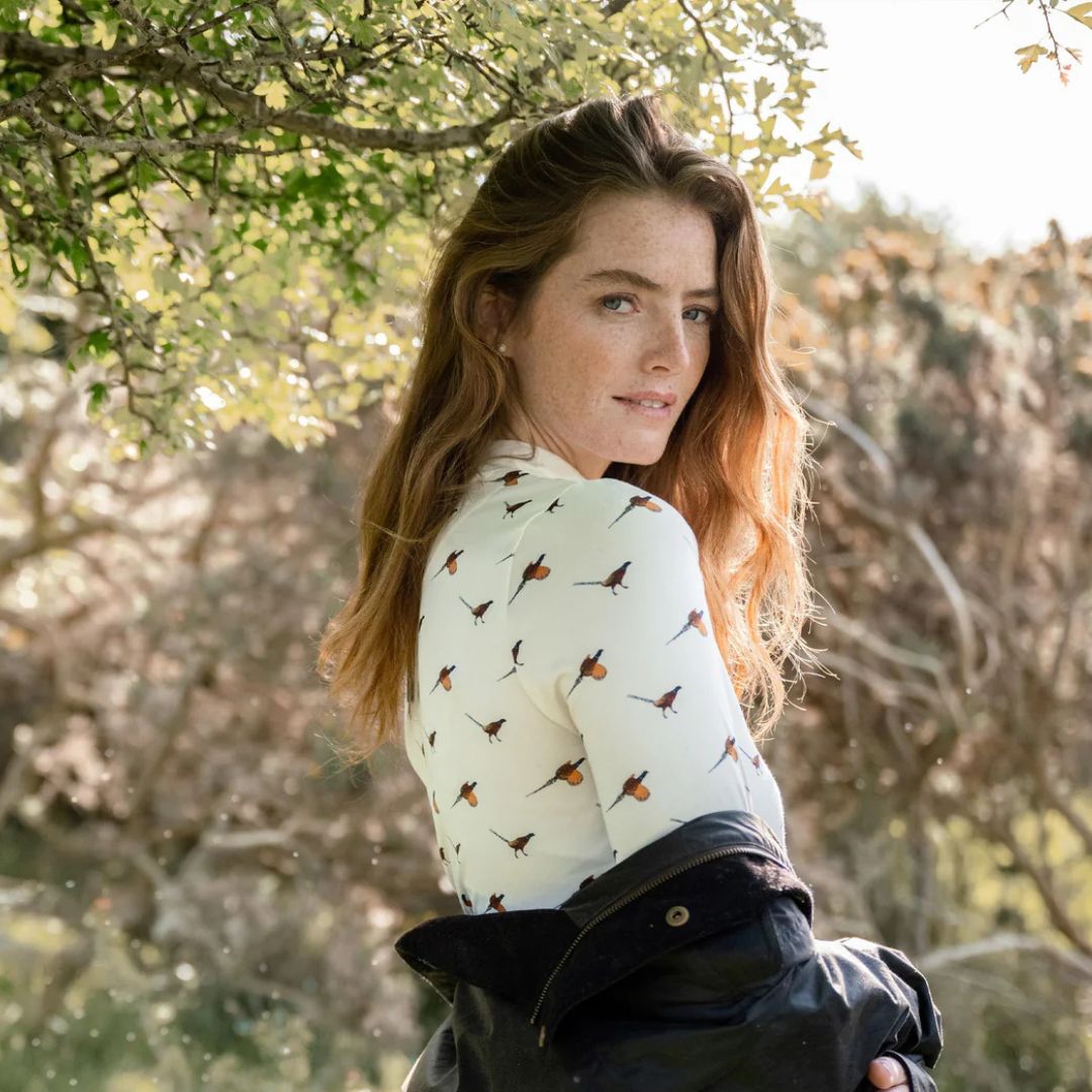 Woman with a floral-patterned shirt standing outdoors with trees in the background