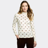 Woman wearing a cream-colored long-sleeve shirt with bird pattern on a white background