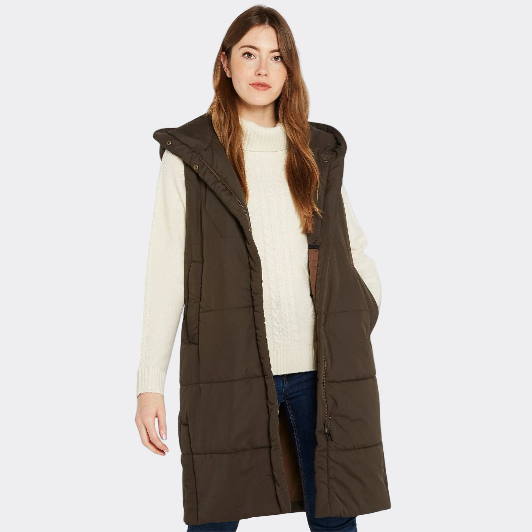 Woman wearing a long brown vest over a white sweater on a white background