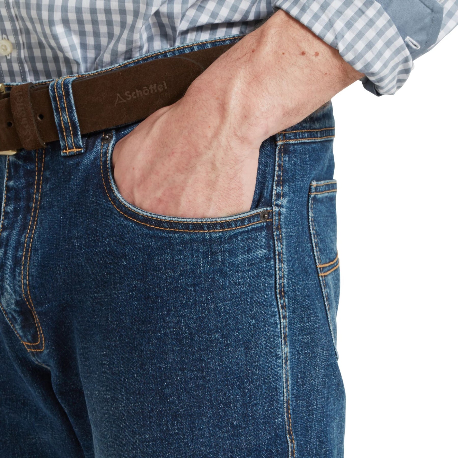 Close-up of a person wearing blue jeans with a Schott belt on a white background