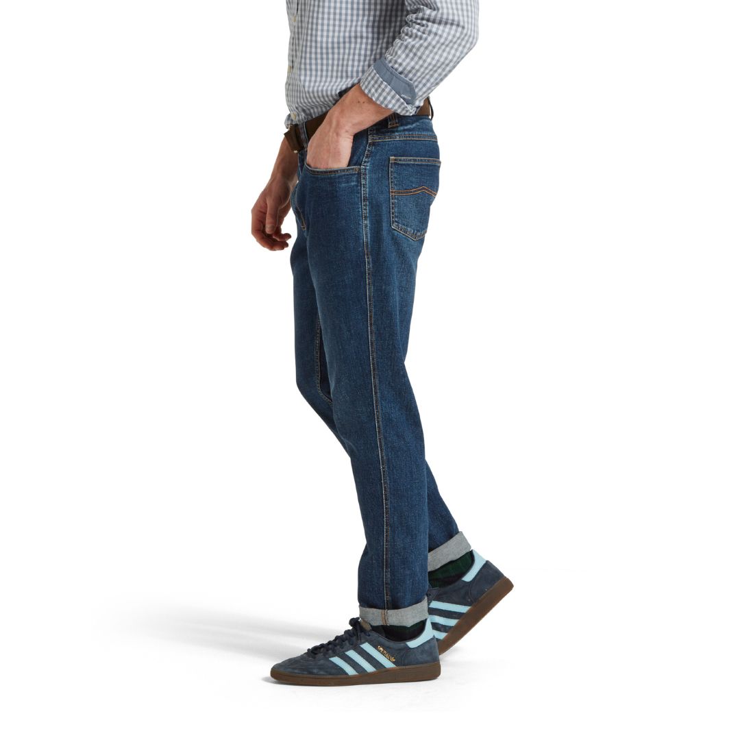 Person wearing blue jeans and Adidas shoes on a white background