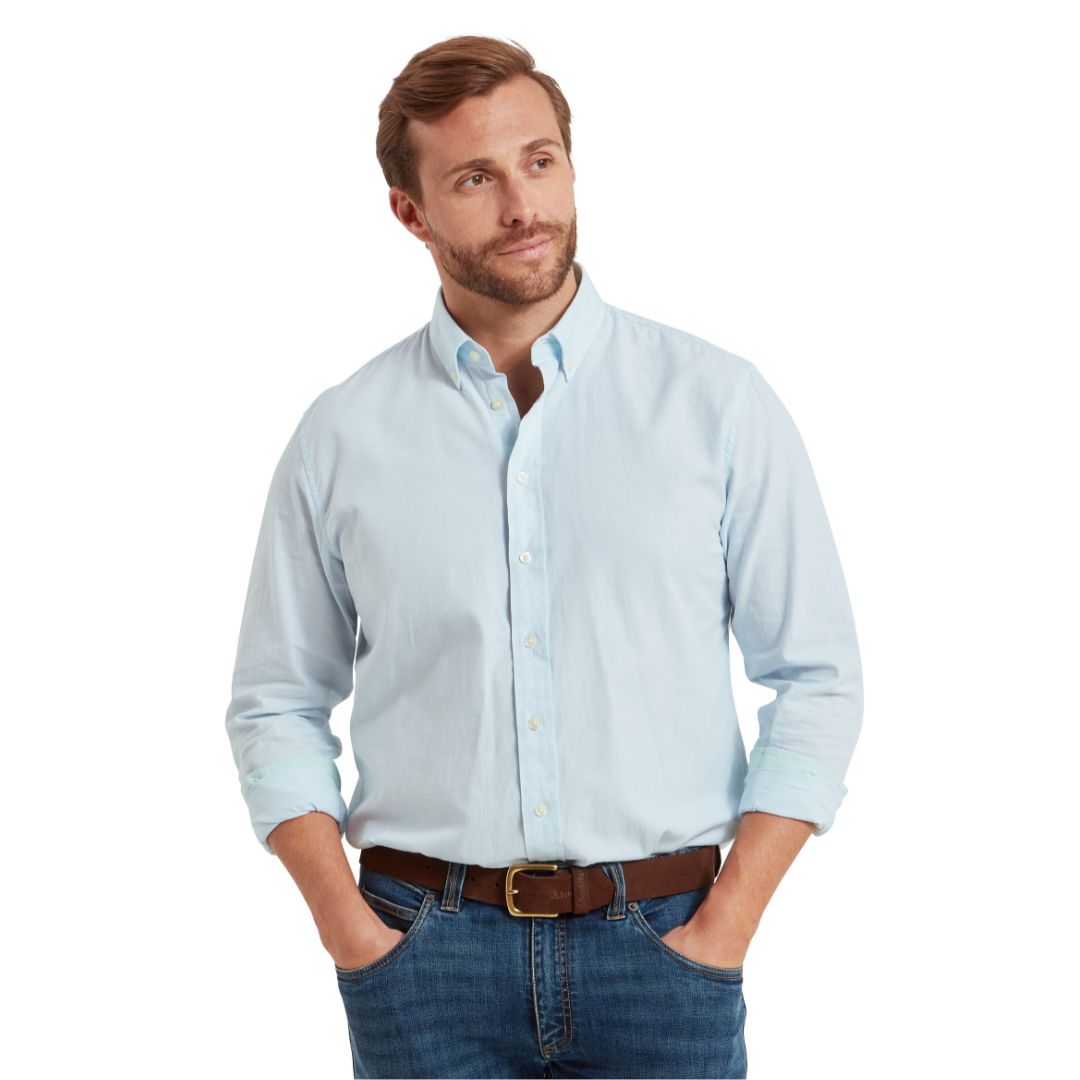Man wearing a light blue button-up shirt and jeans on a white background
